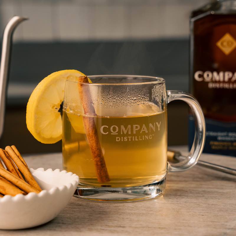 Bourbon hot toddy with cinnamon and lemon garnish.